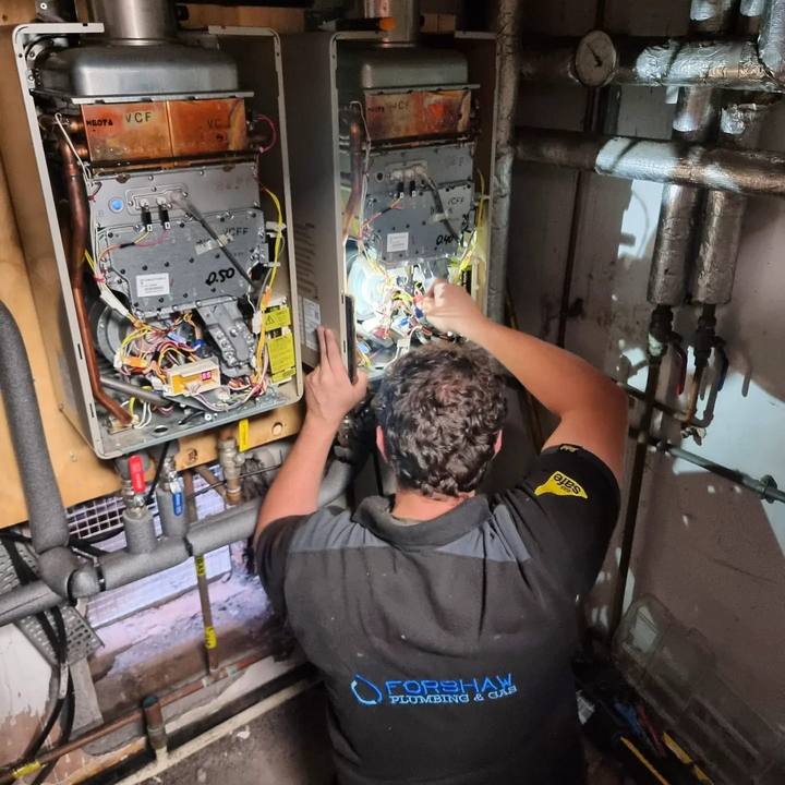 A Forshaw engineer working on twin wall-mounted commercial boilers