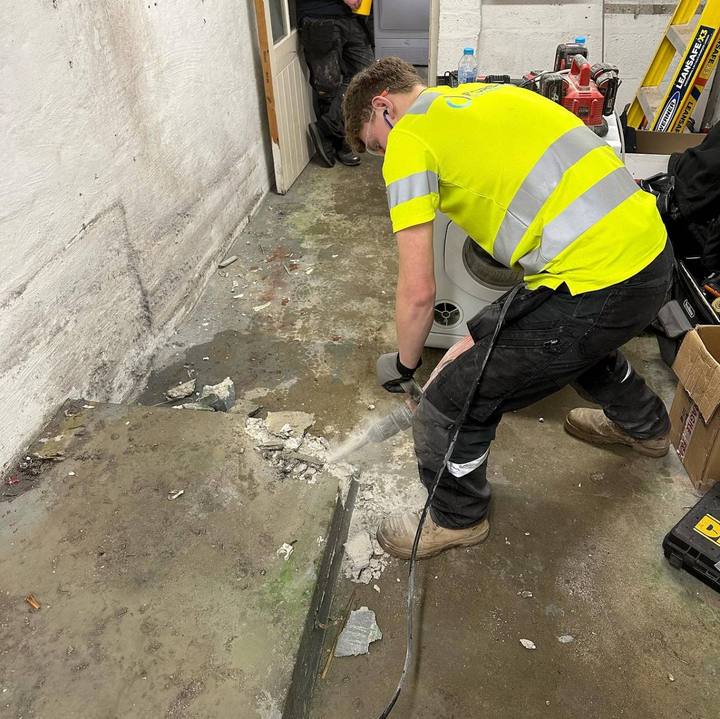 A Forshaw apprentice in hi-vis breaking out a concrete floor for drainage