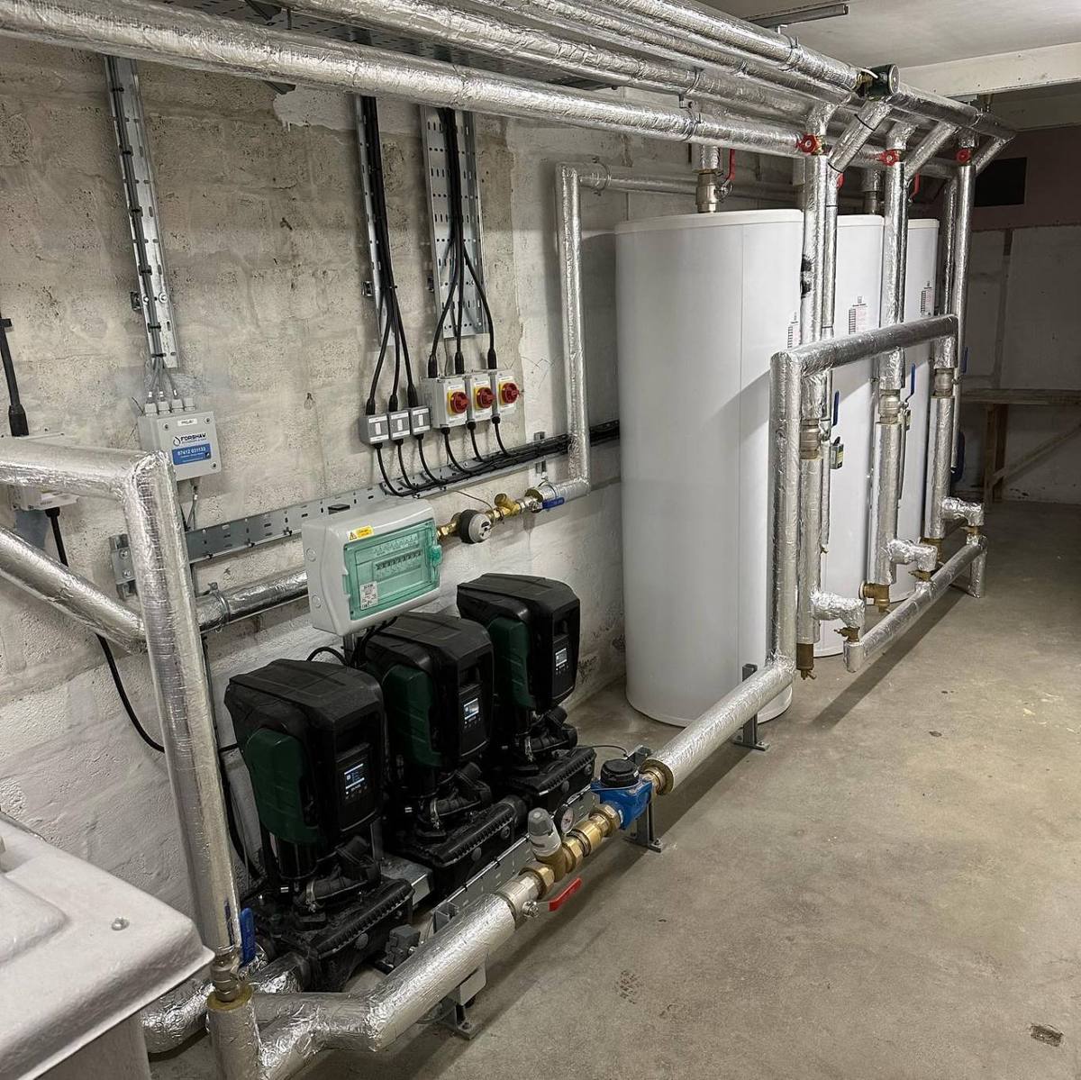 A Forshaw plant room install with GRP water tanks, a triple booster pump set and hot water calorifiers