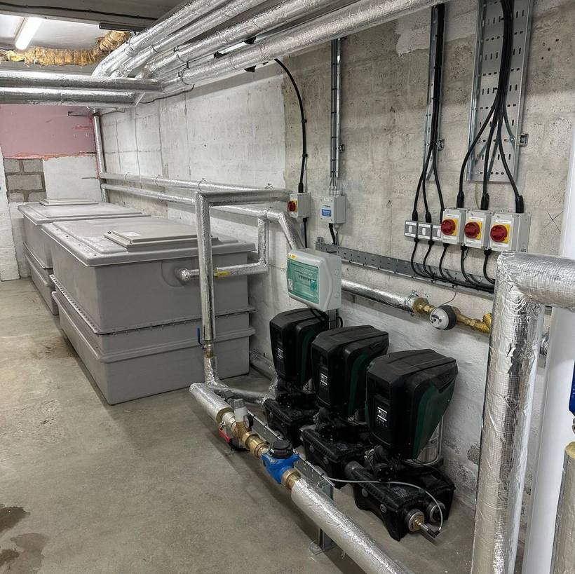 GRP cold water storage tanks and a triple booster pump set in a plant room